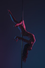 beautiful flexible young woman exercising with pole on blue