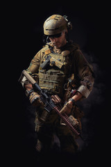 special forces soldier of the united states poses with a rifle on a black background
