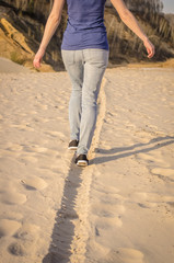 A woman in jeans walks the sand