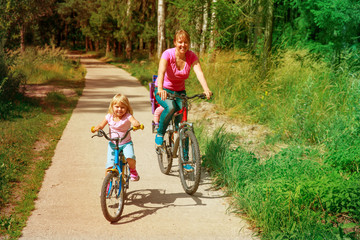 mother with kids riding bikes in summer nature