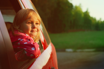 happy little girl travel by car in sunset nature