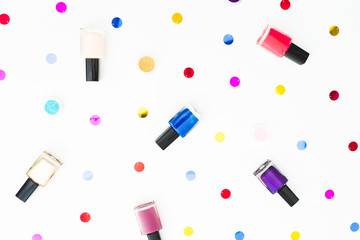 Beauty composition with nail polish and confetti on white background. Flat lay, top view. Beauty concept for woman