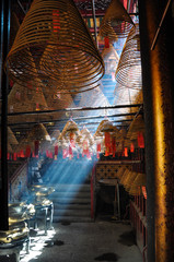 Naklejka premium Light pouring through the incense smoke of a temple in Hong Kong