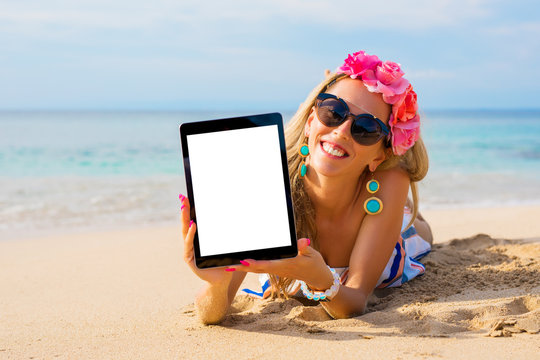 Hipster girl showing empty vertical tablet on the beach, mockup for design.