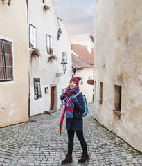 Obraz na płótnie Canvas Woman tourist in a coat with a backpack travels in the old streets of Cesky Krumlov