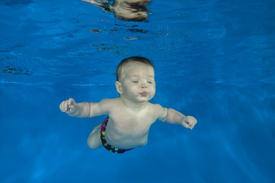 little 4 months boy learns to swim underwater in the pool