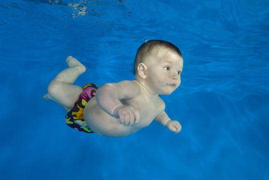 little 4 months boy learns to swim underwater in the pool