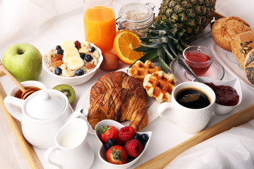breakfast in bed with fruits and pastries on a tray -waffles, croissants, coffe and juice