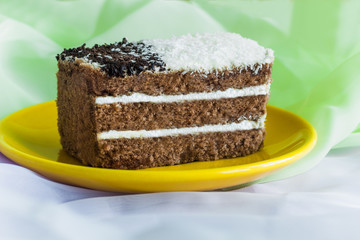 chocolate cake with a layer of whipped cream decorated with coconut and chocolate flakes