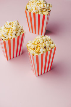 Popcorn in red and white cardboard box on the pink background.