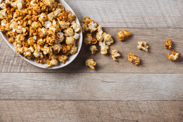 Caramel opcorn in bowl on the wooden table.