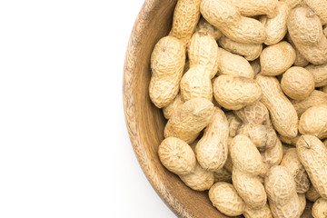 Unshelled peanuts top view in a wooden bowl isolated on white background.