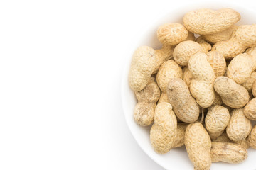 Unshelled peanuts top view in a porcelain bowl isolated on white background.