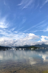 Vertical mountain, blue sky, boats, yacht and sailboats on lake
