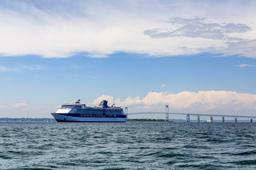 Fototapeta na wymiar Blue and White Cruise Ship by Bridge in Newport