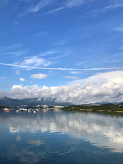 Vertical mountain, blue sky, boats, yacht and sailboats on lake