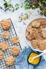 Oatmeal cookies cool down on a metal grate and lie on a pink plate on a marble table next to flowers and apricot jam vertical