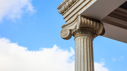Marble pillar detail. Ancient ionic column of white ornate marble. Blue sky, under, close up view,...