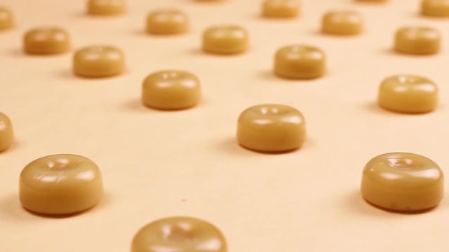 Sweet caramel candys on pastel yellow surface.