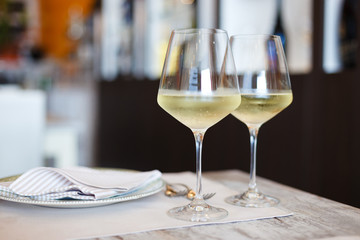 Two Glasses of White Wine on dining table in the restaurant, blurred bokeh background. 