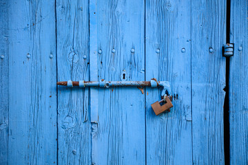 Wooden bright blue, empty, old door for background. Rusty latch, padlock. Close up, banner, details