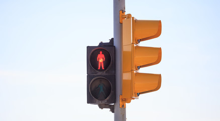 Red traffic light stops pedestrian for the crossing of the road. Sky backdrop, space, banner, detail