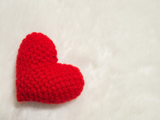 Fototapeta premium handmade red yarn heart on white wool. the red heart on the left of picture and background copy space for text. Valentines day, love concept and love background