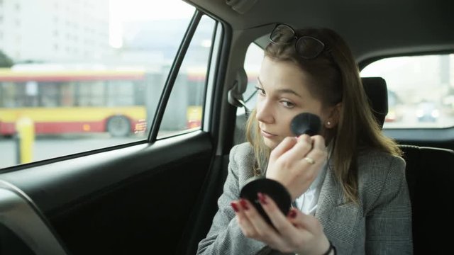 Businesswoman Putting on Makeup in the Moving Car