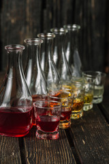 Assorted alcoholic cordials in glasses and decanters on dark wood background