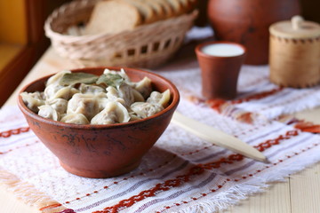 Russian dumplings. Dumplings in a clay bowl on the table by the window.