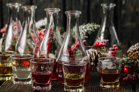 Assorted alcoholic cordials in glasses and decanters with Christmas decorations on dark wood background