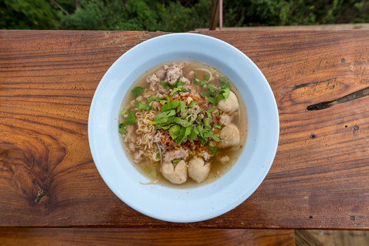 Spicy hot Pork Tom Yum Noodle on the wooden background, Signature food of Thailand