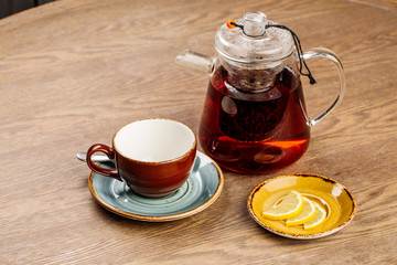 glass teapot with some tea inside on on wooden table