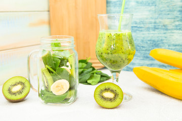 Tropical Healthy Smoothie with fresh kiwi, banana and spinach against a light colored wooden wall