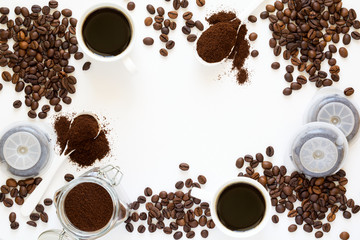 Background with assorted coffee: cups of espresso, coffee beans, powder and capsules on white background. Space for copy. Top view. Flat lay