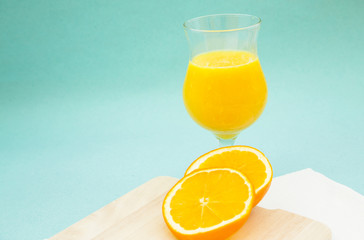 Fresh Tropical Smoothie Concept. A glass of smoothie cocktail with fresh orange on a wooden cutting board, light blue background. Healthy Food, Diet, Fitness