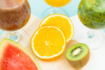 Tropical Smoothie Cocktail with fresh watermelon, orange, grapes and bananas. Light blue background, top viewHealthy food, Diet, Fitness, Dessert Concept
