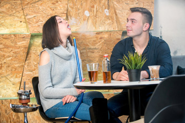 couple relaxing and smoking hookah at caffe bar
