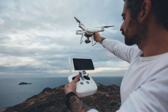 Professional drone pilot or stock photographer, prepares to fly high technology futuristic drone into air, sets up controls and remote connection. Ready to explore nature and cliffs from top