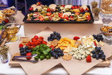 Different types of cheese cut into triangles lie on paper with strawberries. different types of cheese
