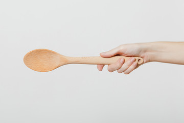 Close up of female hand horizontal holding wooden kitchen spoon for stirring and tasting food in the kitchen isolated on white background. Kitchen utensils concept. Copy space for advertisement. - Powered by Adobe