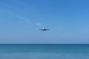 Airplane landing over the blue sea