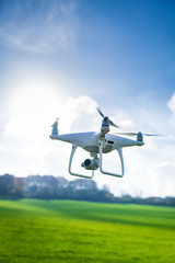 Picture of flying white drone camera in front of trees - 189494945