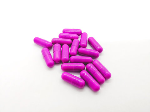 Medication and healthcare concept. Many purple capsules of Clindamycin 300 mg. isolated on white background, used to treat serious infections caused by bacteria. Selective focus and copy space.