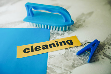 Cleaning concept light concrete background with blue cleaning tools and Cleaning inscription, top...