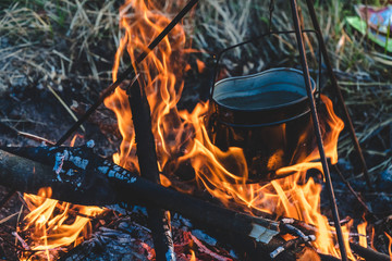 Close-up view of a fireplace kitchen with bunch of burning firewood to boil water in the old aluminum kettle. cooking way is still retain in many countryside, travel equipment, disinfection water