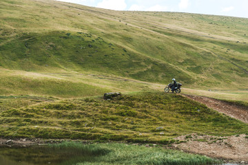 Obraz premium Motorcyclist on a mountainous road, cold overcast weather. Extreme sport, active lifestyle, adventure touring concept. High mountains, dirt roads. enduro off road touring