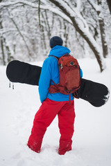 Fototapeta na wymiar Snowboarder with backpack stands in the forest after snowfall