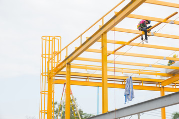 Manpower painting yellow color metal structure on roof top