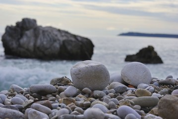Gray pebbles with sea and rocks on the background